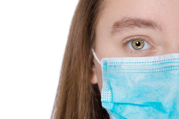 istock Young girl in a protective mask with beautiful eyes on a white background 1204557378