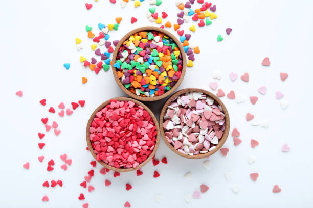 istock Colorful heart shaped sprinkles in bowls on white background 1204559172
