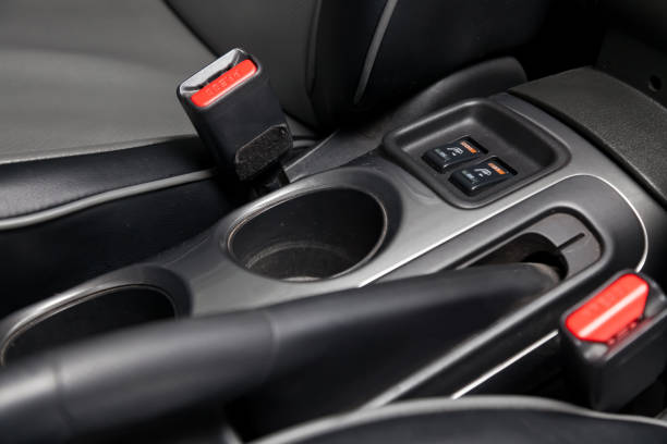 istock Interior view with leather seats , two cup holders, red safety belt locks and seat heater buttons of black used car stands in the showroom after dry washing before sale 1204562445