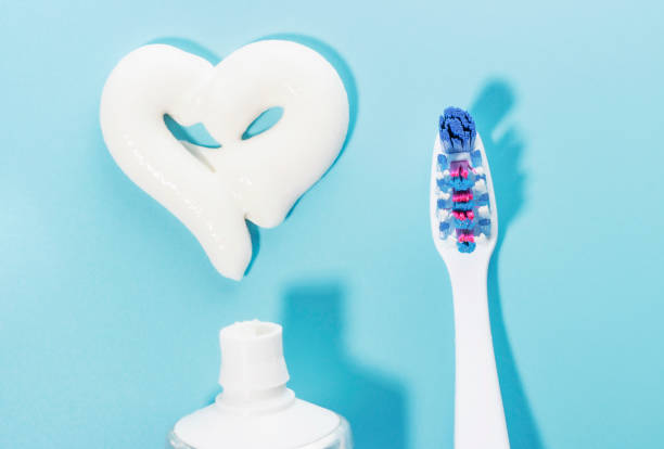 istock Heart shaped toothpaste and toothbrush on blue background, dental care concept. 1204564167