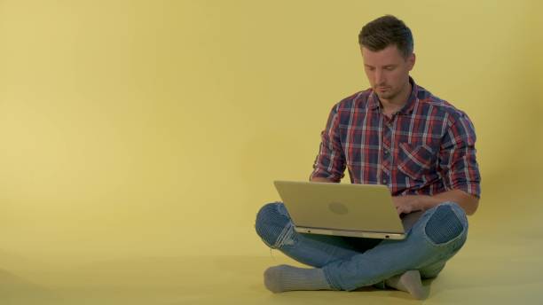 istock Attractive young man chatting with friends on computer while sitting on the floor 1204564759