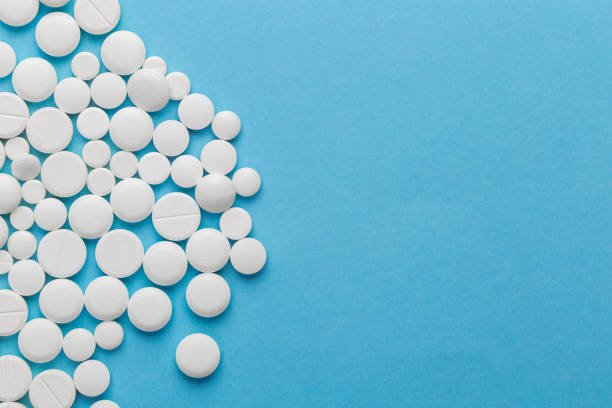 istock scattered white pills on a blue table. Layout for special offers such as advertising or other ideas. The concept of medicine, pharmacy and healthcare. Space for copy. 1204572805