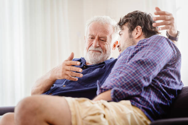 starzec poważna dyskusja z młodszym mężczyzną w pomieszczeniu, wielki ojciec poważne rozmowy z synem w domu. - worried sadness men senior adult zdjęcia i obrazy z banku zdjęć