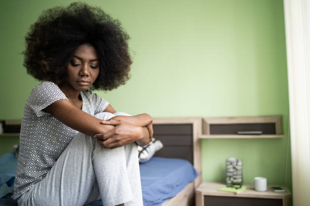 istock Sad afro woman sitting on a bed 1204573525