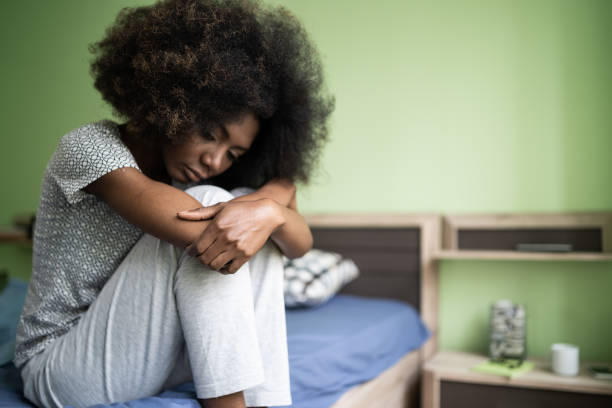 istock Sad afro woman sitting on a bed 1204573527