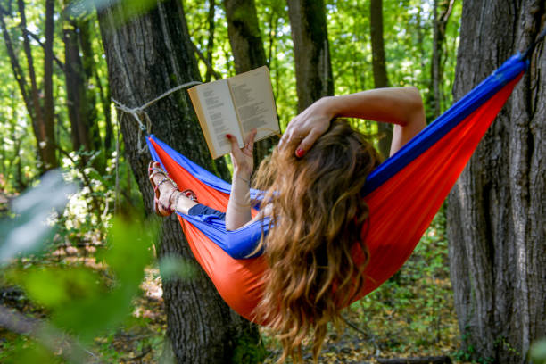 istock Woman reading a book in hammock. 1204573834