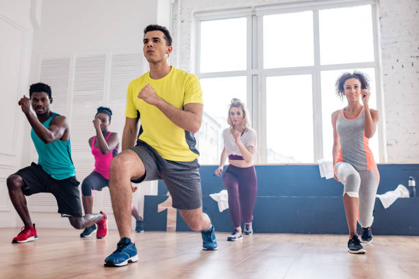 istock Low angle view of handsome trainer performing zumba with multiethnic dancers in dance studio 1204577441