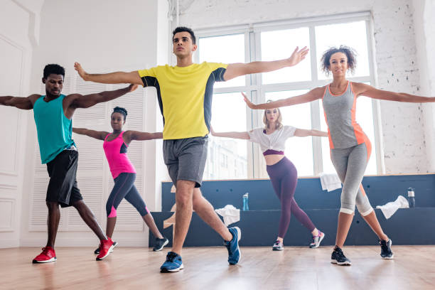 Low angle view of handsome trainer performing zumba with multicultural dancers in studio Low angle view of handsome trainer performing zumba with multicultural dancers in studio dance studio instructor stock pictures, royalty-free photos & images