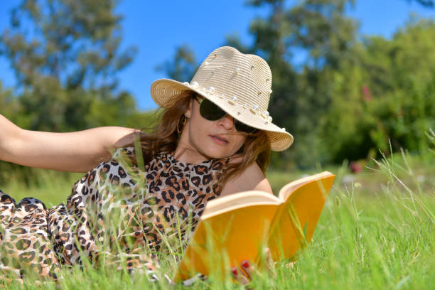 istock Woman lying on the grass is reading a book. 1204580081
