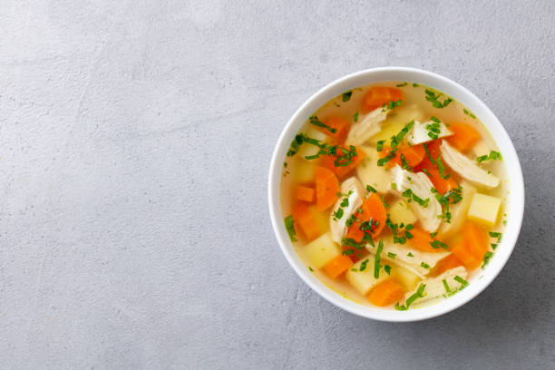 istock Chicken soup with vegetables in white bowl. Grey stone background. Copy space. Top view. 1204580210