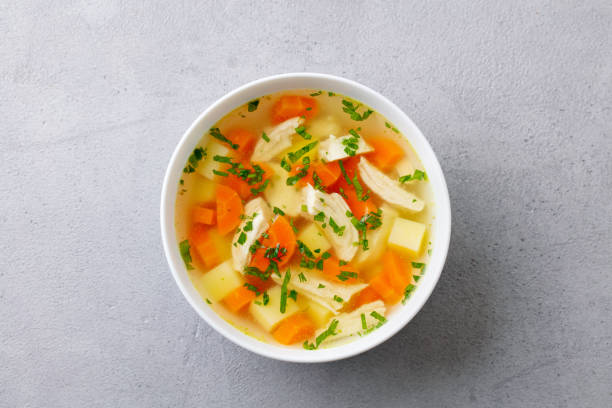 sopa de pollo con verduras en tazón blanco. fondo de piedra gris. vista superior. - cooked soup food bowl fotografías e imágenes de stock