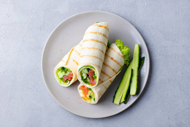 Wrap sandwich, roll with fish salmon and vegetables. Grey background. Top view. Wrap sandwich, roll with fish salmon and vegetables. Grey background. Top view. wrap sandwich photos stock pictures, royalty-free photos & images