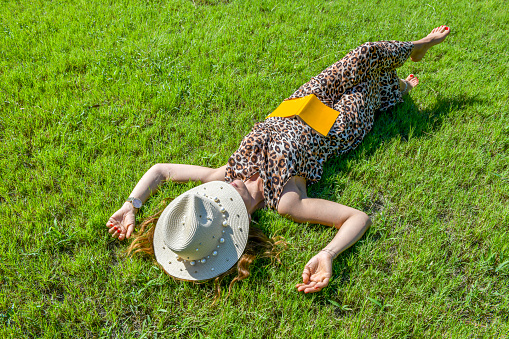 Woman sleeping while reading a book on the grass.