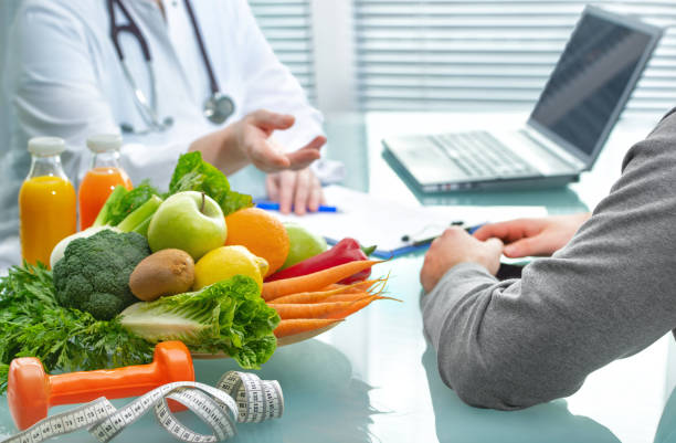 栄養士は野菜や果物と健康的な食事について患者に相談しています - スポーツクリニック ストックフォトと画像