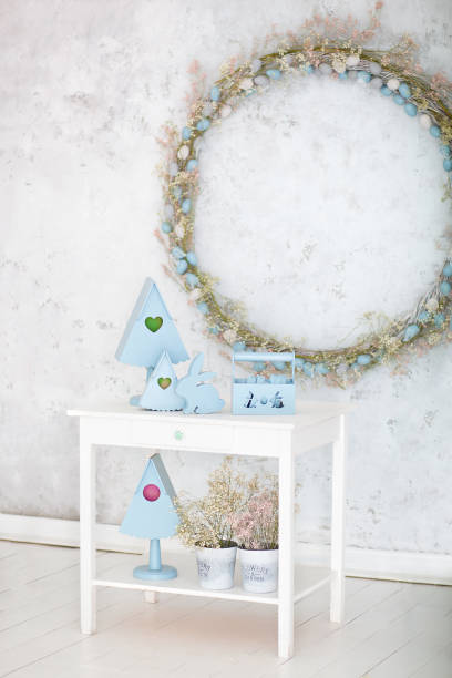 Stylish home decor in blue is a wooden basket, decorative nesting boxes and a cute rabbit. Easter decorations. Summer village composition with a wooden nesting box on a white table. spring room decor elegante decoración del hogar en azul es una cesta de madera, cajas de anidación decorativas y un conejo lindo. decoraciones de pascua. composición de pueblo de verano con una caja de anidación de madera sobre una mesa blanca. decoración de la habitac