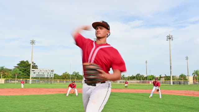 Hispanic baseball pitcher in windup and throwing