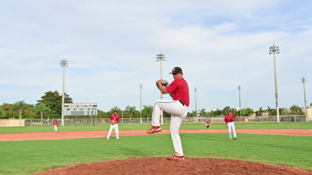 Hispanic baseball player delivering a pitch from the mound