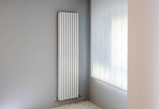 istock white radiator on gray wall with window 1204585770