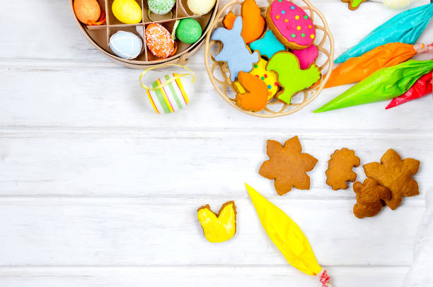 Child Decorating gingerbread cookies for Easter with color icing, Top view of hands, selective focus and place for text. Holidays concept