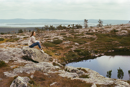 Young Caucasian woman looking at scenic view from mountains in Finland