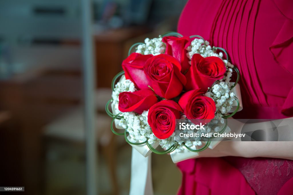 Foto de Noiva Segurando Buquê De Casamento Vermelho Rosa De Rosas E Flores  De Amor A Noiva De Vestido Vermelho Segura Em Suas Mãos Um Elegante Buquê  De Noiva De Rosas Vermelhas