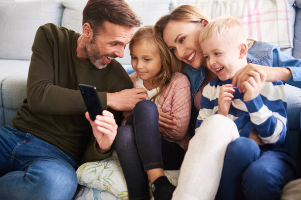 istock Family using mobile phone in living room 1204594766