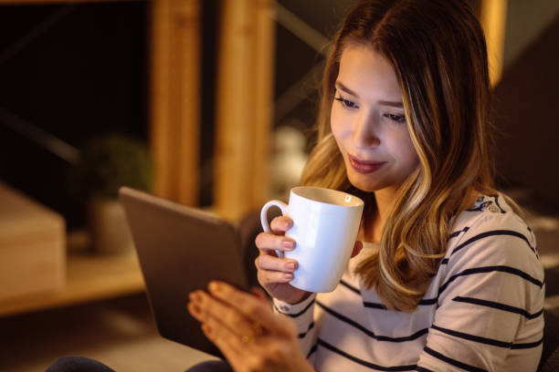 istock Young woman using digital tablet and drinking tea at night 1204596555