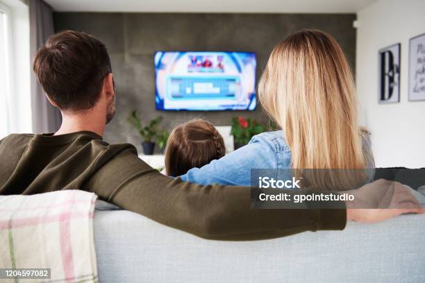 Rear View Of Family Watching Tv In Living Room Stock Photo - Download Image Now - Watching TV, Family, Movie