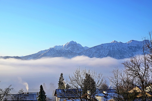 A dense fog at the Allgäu Alps with the Hopfensee in the foreground. Ost-Allgäu, Bavaria, Germany.