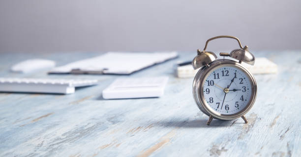 istock Alarm clock with business objects on the desk. 1204601177