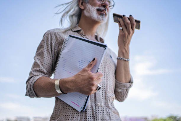 Modern Hispanic professor holding a mobile phone while recording a voice message, on the move.