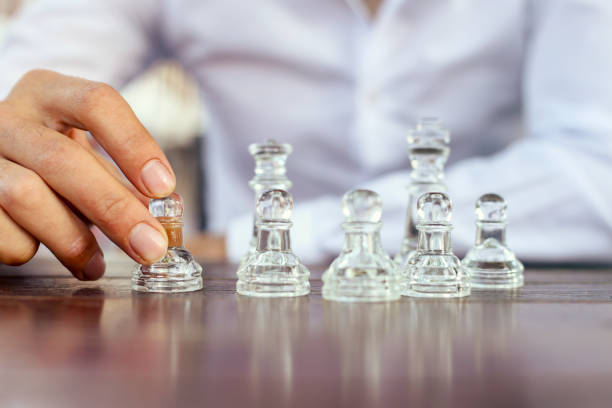 istock a businessman with clasped hands planning strategy with chess figures on an old wooden table. 1204603091