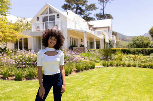 Weekend fun at home together. Portrait of a mixed race woman standing in the garden outside her luxury home and smiling to camera