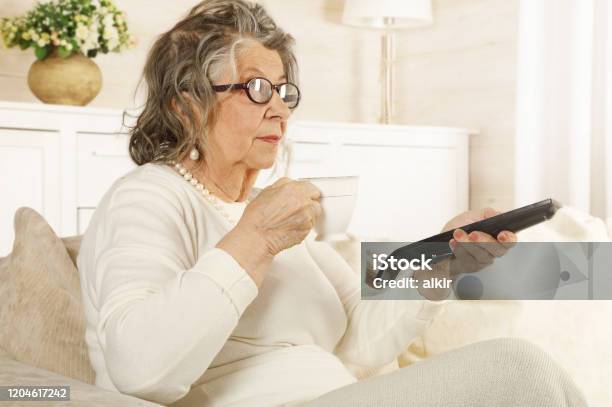 Una Anciana Con Un Control Remoto De Tv En La Mano Foto de stock y más banco de imágenes de Adulto - Adulto, Adulto maduro, Arrugado