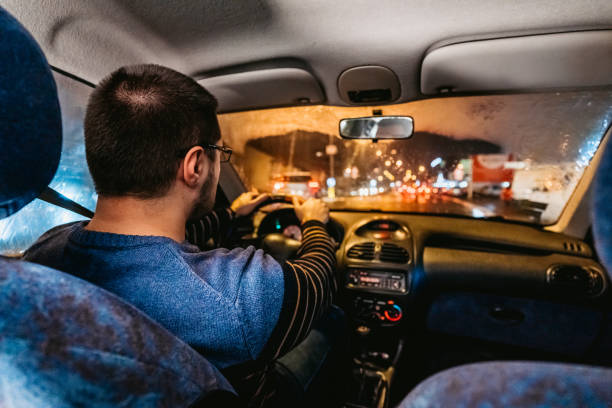 istock Man driving car on city streets 1204620353