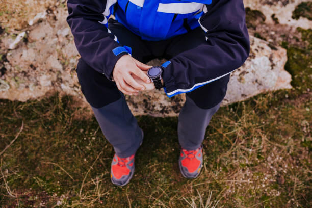 młody turysta sprawdza inteligentny zegarek na szczycie góry. pochmurny dzień - men jogging running sports training zdjęcia i obrazy z banku zdjęć
