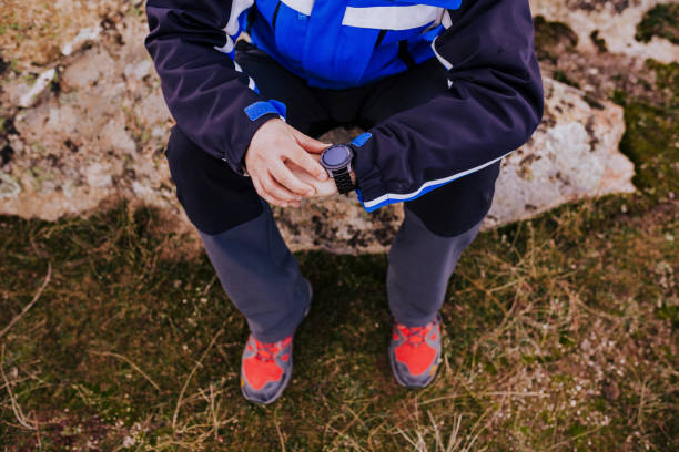 jovem caminhante homem verificando relógio inteligente no topo da montanha. dia nublado - men jogging running sports training - fotografias e filmes do acervo