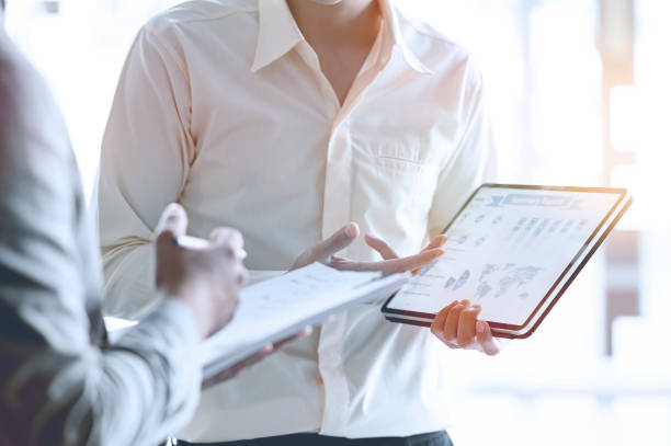 istock Cropped shot of two businessman using tablet discussing about business plan while standing in modern office. 1204620634