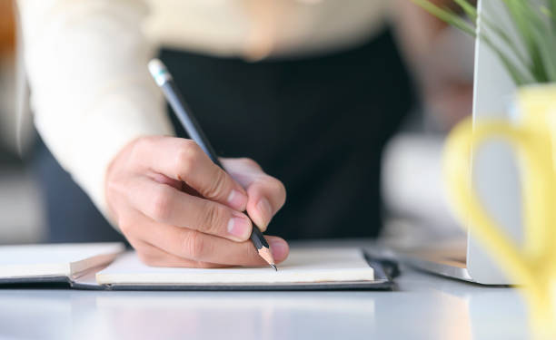 istock Closeup view of man hand writing on notebook with pencil. 1204620950