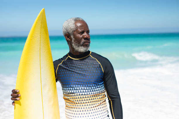 istock Old man with a surfboard at the beach 1204621794