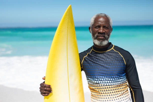 istock Old man with a surfboard at the beach 1204621810