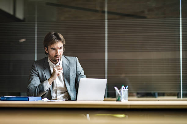 istock Thoughtful male entrepreneur reading an e-mail on laptop in the office. 1204623729
