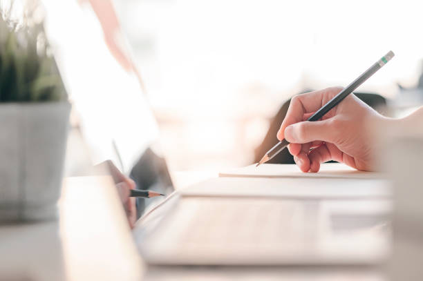 istock Closeup view of man hand writing on notebook with pencil. 1204624145