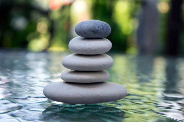 istock Stone cairn on green blurry background, light pebbles and stones 1204624490