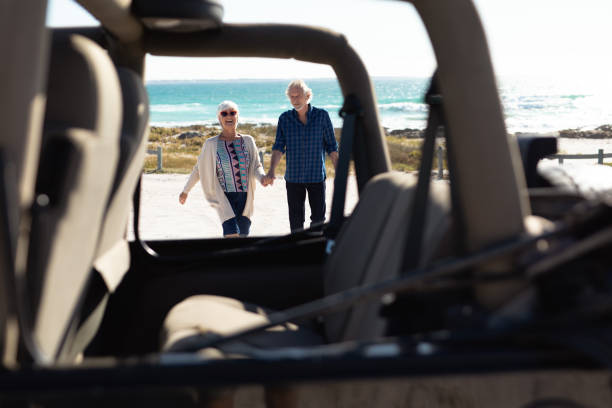 istock Old couple with a car at the beach 1204626111