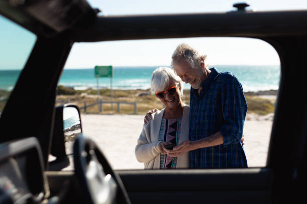 istock Old couple with a car at the beach 1204626114