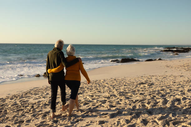 istock Old couple walking at the beach 1204628177