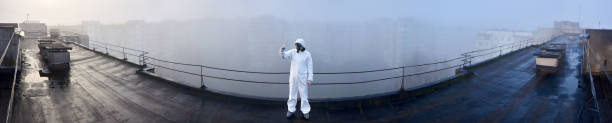 Worker scientist wearing protective coverall and gas mask doing ecological tests on the roof