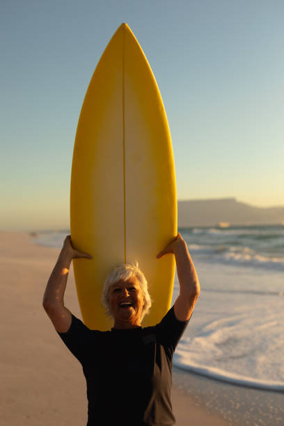 istock Old woman carrying a surfboard 1204628464