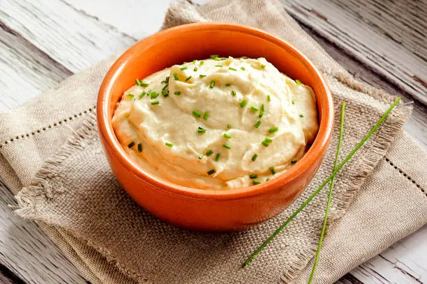 Mashed cauliflower. Gluten-free side dish. For vegetarians, ketogenic diets and paleo diets. A portion is served in a deep bowl and decorated in a rustic style. Close up and horizontal orientation.
